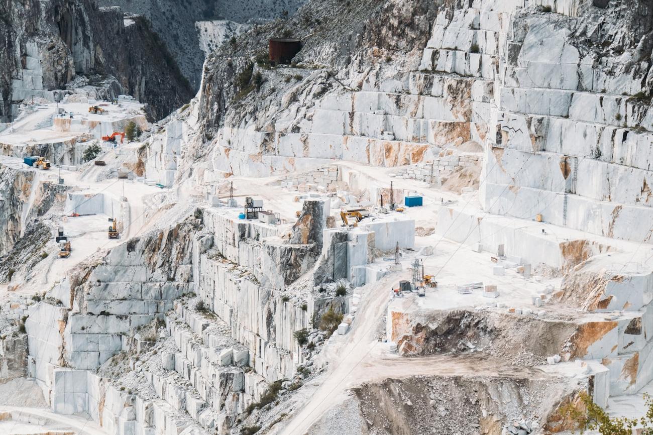 The cut terraces of a white marble quarry, blocks squared off along the rock face